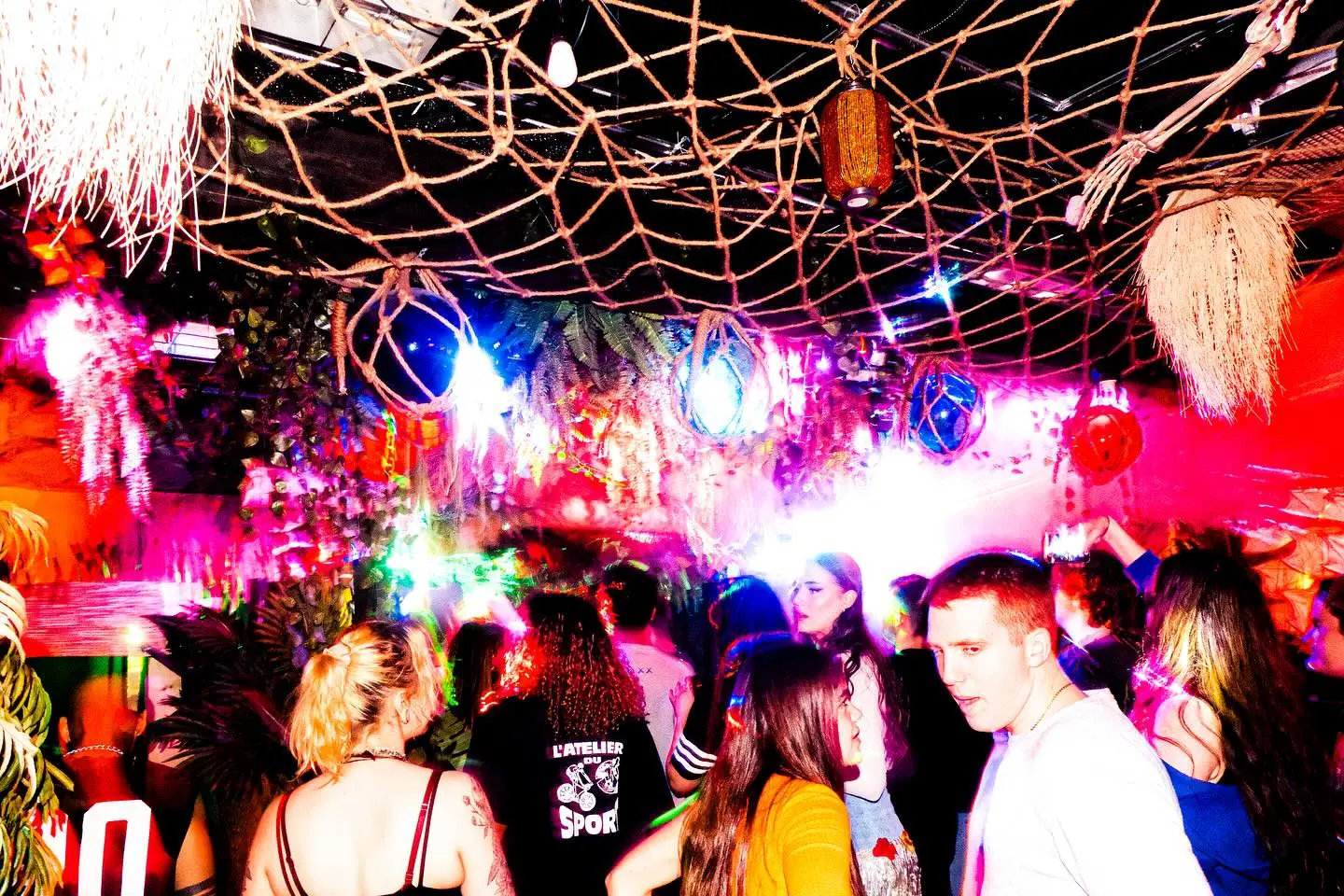 The first Frequency Shift dancefloor glowing red, blue, and white beneath Poa Tiki’s rope ceiling.